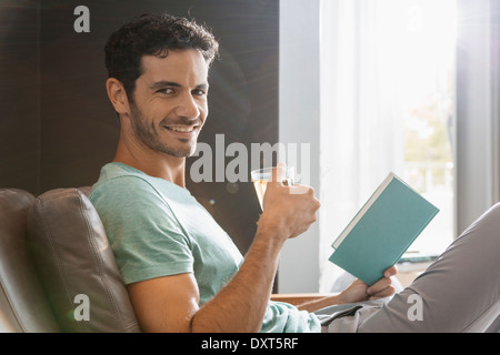 Portrait of smiling man drinking tea and reading book Banque D'Images