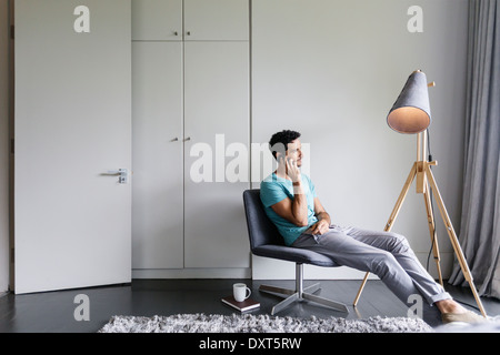 Man talking on cell phone in living room Banque D'Images