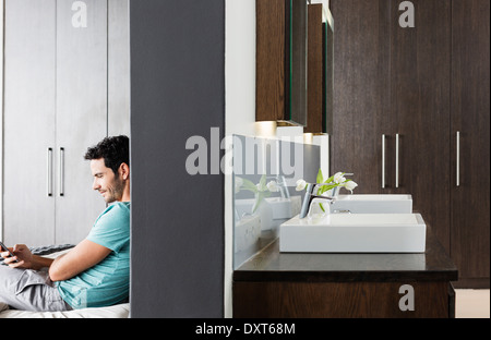 Man texting with cell phone in bedroom Banque D'Images