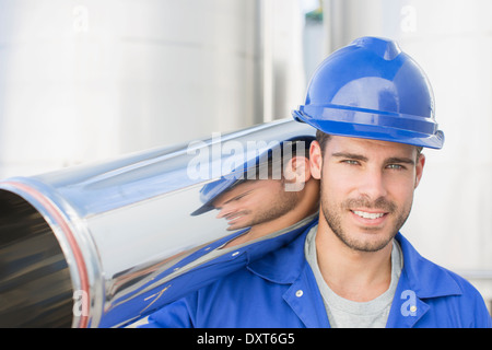 Portrait of smiling worker carrying tube en acier inoxydable Banque D'Images