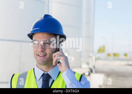 Close up of worker talking on cell phone in front of tour de stockage d'ensilage Banque D'Images