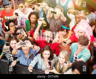 Téléphones portables avec appareil photo avec des fans cheering at music festival Banque D'Images