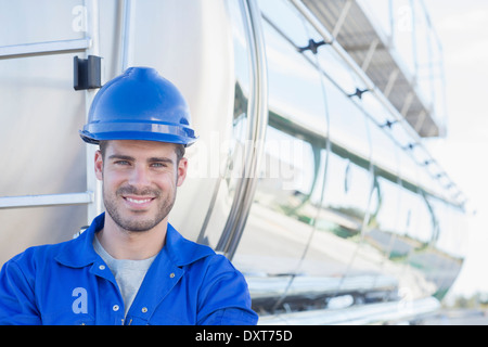 Portrait of smiling worker à l'arrière du camion-citerne de lait en acier inoxydable Banque D'Images