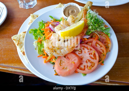 Brochette de gambas grillées ou les crevettes sur une salade verte avec des tomates fraîches. À partir de la Tree House Café sur l'île Salt Spring. Banque D'Images