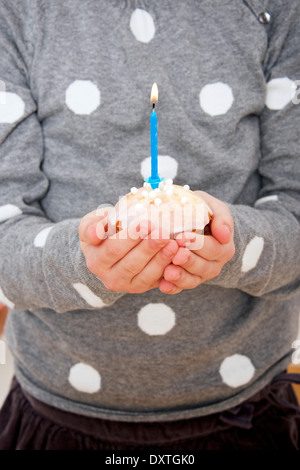 Sur l'enfant d'anniversaire holding cupcake avec bougie allumée, Munich, Bavière, Allemagne Banque D'Images