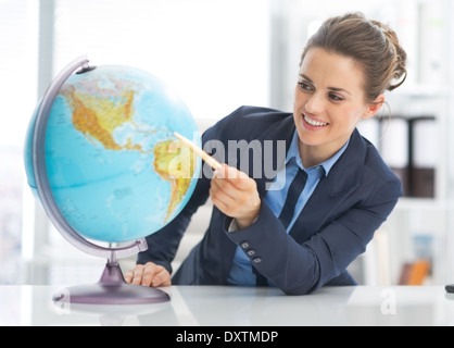 Portrait of happy business woman pointing sur terre globe Banque D'Images