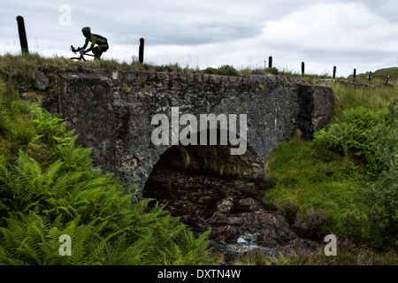 Un cycliste traverse un pont sur la route la plus longue ascension en Lochcarron, Ecosse Banque D'Images