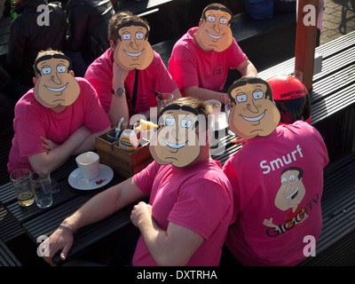 Un groupe d'hommes en un front de mer de Brighton bar pour un enterrement de vie de garçon, portent des masques de boue, personnage de la série Family Guy Banque D'Images