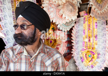 L'Inde, Dehradun. Shopowner Sikh de guirlandes vente billets Roupie comme cadeaux de mariage pour la mariée. Banque D'Images