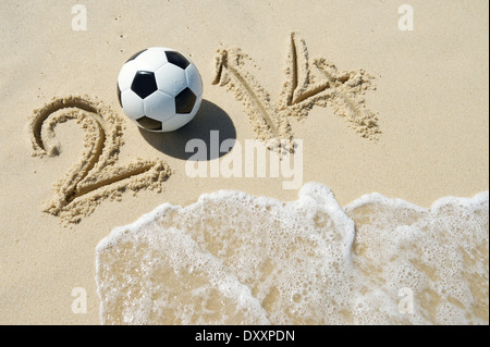Message pour 2014 faite avec football ballon de football à la plage avec des vagues entrant à Rio de Janeiro Brésil Banque D'Images
