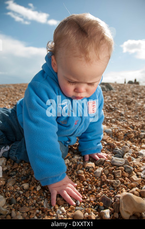 Un mignon petit garçon sur une plage de galets Banque D'Images