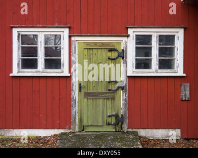 La porte verte avec funny horse shoe sur charnières en forme de vieille ferme rouge blanc outhouse, cadres de fenêtres, Moss Norvège Banque D'Images