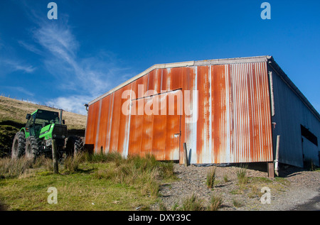 La rouille rouillé en tôles ondulées rouillées avec hangar agricole tracteur stationné à l'extérieur près de Bugeilyn Powys Pays de Galles UK Banque D'Images