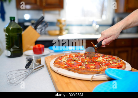 La coupe d'un homme sans gluten chaud des pizzas sur une pierre de cuisson dans la cuisine à la maison Banque D'Images