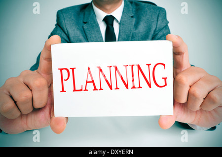 Businessman sitting in a 24 montrant une pancarte à la planification de texte écrit en c Banque D'Images