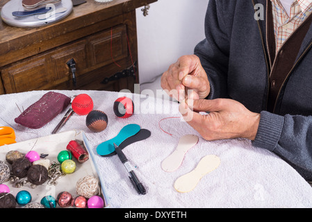 Image main d'hommes experts boules pelote couture, équipements sportifs traditionnels méditerranéens Banque D'Images