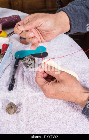 Image main d'hommes experts boules pelote couture, équipements sportifs traditionnels méditerranéens Banque D'Images