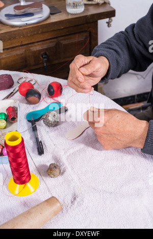 Image main d'hommes experts boules pelote couture, équipements sportifs traditionnels méditerranéens Banque D'Images