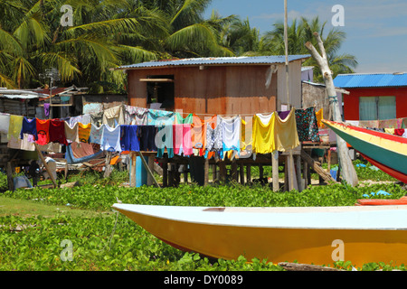 Bateaux et cocotiers entourent un village de pêcheurs et leurs vêtements colorés sur une ligne de séchage sur une île de Malaisie. Banque D'Images