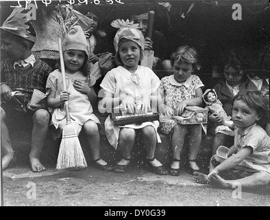 Une photographie de Sam Hood datant de 1934 montrant des enfants à une fête de Noël, chaque détenteur présentant des cadeaux. La scène capture l'innocence et la joie de l'enfance, avec certains enfants en costumes et d'autres pieds nus. Il offre un aperçu des célébrations de Noël dans les maisons d'enfants de Nouvelle-Galles du Sud, avec des jouets et des vêtements vintage. Banque D'Images