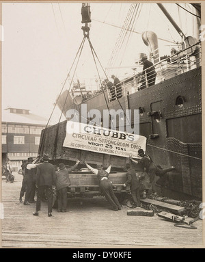 Cette photographie, prise dans les années 1920, montre la livraison d'un coffre-fort Chubb à commercial Banking Co. L'image, capturée par un photographe inconnu, reflète l'importance des opérations bancaires sécurisées pendant cette période, préservée par la Bibliothèque d'État de Nouvelle-Galles du Sud. Banque D'Images