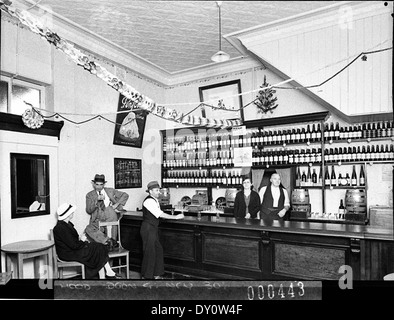 Cette photographie de janvier 1939 par Sam Hood montre le propriétaire et sa femme servant les clients dans un bar à vin, avec les vins de Penfold en évidence. L'image capture l'atmosphère sociale de l'époque. Banque D'Images