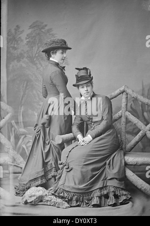 Ce portrait capture Mlle Alice, surnommée « la Rose blanche de Sydney », et sa sœur Margaret Halloran, toutes deux de Burwood, Nouvelle-Galles du Sud. Prise vers 1877, l'image les montre dans des robes et des chapeaux identiques, capturés dans un négatif en verre plat par Freeman & Co. Cette photographie historique met en lumière les tendances de la mode de la fin du XIXe siècle. Banque D'Images