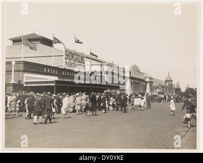 Cette photographie des années 1930 de Sam Hood montre l'atmosphère vibrante du parc d'expositions de la Royal Agricultural Society, avec ses pavillons et ses foules. L'image capture un moment clé dans les expositions agricoles, mettant en valeur l'intérêt et la participation du public à ces événements. Banque D'Images