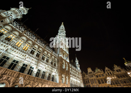Grand Place illuminée la nuit Bruxelles Belgique | BRUXELLES — L’éclairage trace la flèche étagée de la tour de l’Hôtel de Ville contre un ciel noir sur la Grand-Place, avec les maisons de guildes brillant le long du bord du square en dessous. La tour, s’élevant de 1449 à environ 96 pieds (96 m), reste la structure la plus haute sur la place et le siège historique du gouvernement de la ville. Banque D'Images