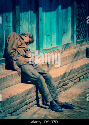 Homme endormi sur les étapes de Bhaktapur, Népal Banque D'Images