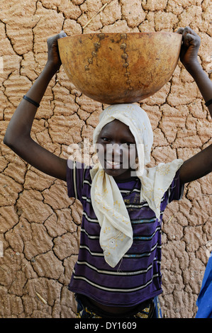 Zinder, NIGER village BABAN TAPKI, jeune femme en face de calebasse avec mur d'argile Banque D'Images
