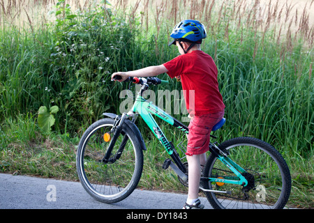 Garçon polonais de 10 ans portant un casque équitation son nouveau vélo Nord vers le bas une route de campagne. Zawady Centre de la Pologne Banque D'Images