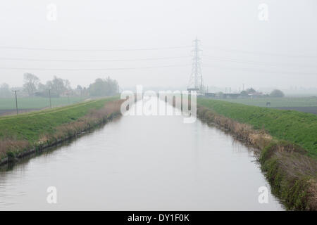 Ely, au Royaume-Uni. 3 avril, 2014. Un canal de drainage dans un ciel chargé de poussière juste après l'aube à Ely dans le Cambridgeshire Fens 3e avril 2014. La brume est causée par les systèmes météorologiques apportant de l'air pollué de l'Europe et la poussière du désert du Sahara. Il a été particulièrement perceptible dans le paysage plat de la fens. Météo de l'Atlantique est mis à rafraîchir l'atmosphère à partir de demain. Credit : Julian Eales/Alamy Live News Banque D'Images