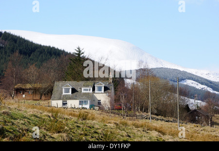 Maison dans la Spittal of Glenshee avec montagnes enneigées derrière, en Écosse. Banque D'Images