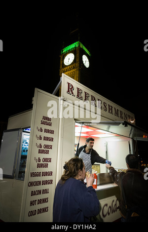 Les clients achètent leurs aliments à partir d'un hot-dog nocturnes et burger stall en face de Big Ben et du Parlement. Banque D'Images