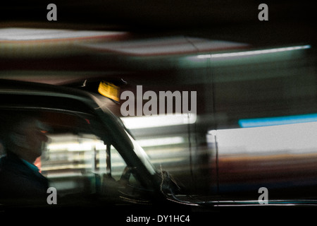 Portrait of a black cab chauffeur de taxi comme il conduit par Londres de nuit. Banque D'Images