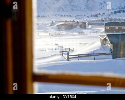 La ferme en montagnes norvégiennes en hiver, vu à travers la fenêtre d'une cabane Banque D'Images