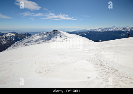 Vue panoramique infinie à partir d'une pente enneigée au printemps avec vallées Brumeux ci-dessous. Méconnaissable d''skieur. Banque D'Images