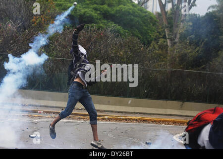 Caracas, Venezuela - le 3 avril 2014 : un manifestant lance une grenade de gaz lacrymogène de la Police nationale dans une manifestation devant l'Université centrale du Venezuela (UCV). Credit : Rafael A. Hernández/Pacific Press/Alamy Live News Banque D'Images