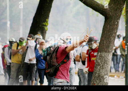 Caracas, Venezuela - le 3 avril 2014 : un manifestant lance une en avec une fronde à la police nationale alors qu'ils retour attaques avec bombe lacrymogène et de balles en caoutchouc à une émeute à l'extérieur de l'Université centrale du Venezuela (UCV). Credit : Rafael A. Hernández/Pacific Press/Alamy Live News Banque D'Images