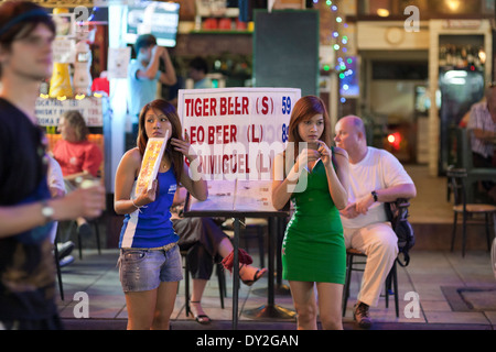 Khao San Road, Bangkok, Thaïlande. Les jeunes femmes la promotion de l'offre de la bière à l'extérieur d'un bar, sortir Banque D'Images