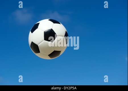 Classique noir et blanc ballon de soccer foot flottant dans un bleu ciel d'été Banque D'Images