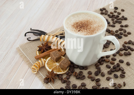 Still Life sur cappuccino tasse décorée avec des céréales, d'épices et de cubes de sucre brun sur la table en bois cirée toile blanche Banque D'Images