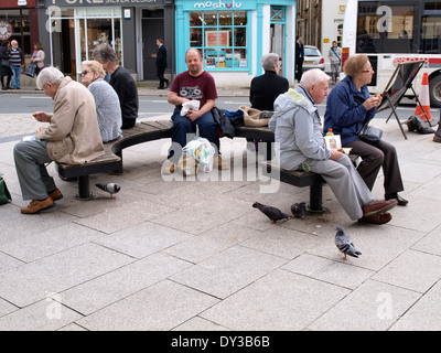 Pigeons sauvages manger morceau abandonné par les gens assis sur banc public, Truro, Cornwall, UK Banque D'Images