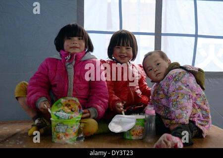 Yongshan, la province chinoise du Yunnan. 5ème apr 2014. Les enfants mangent des nouilles instantanées à un règlement site dans quake-hit Baisheng Village de Yongshan County, au sud-ouest de la province chinoise du Yunnan, le 5 avril 2014. Au moins 25 personnes ont été blessées et 21 000 déplacés en raison de la 5.3-magnitude tremblement de terre qui a frappé le comté tôt le samedi. © Hu Chao/Xinhua/Alamy Live News Banque D'Images