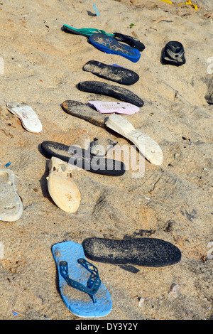 Les bouteilles en plastique, les emballages intérieurs de chaussures et autres déchets rejetés par la mer avec plage de sable à marée basse Banque D'Images