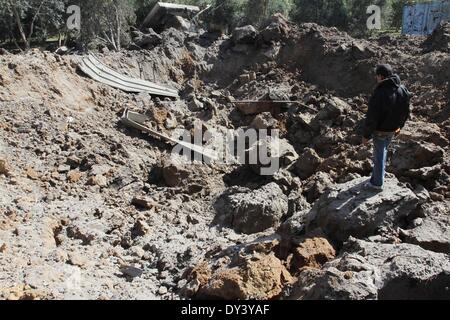 La ville de Gaza, bande de Gaza, territoire palestinien. 6ème apr 2014. Un Palestinien cherche sur le dommage suite à une frappe aérienne israélienne sur les terres agricoles dans la région de Beit Hanoun au nord de la bande de Gaza, le 6 avril 2014. L'aviation israélienne a attaqué plusieurs sites dans la bande de Gaza Dimanche, sources des deux côtés a déclaré, quelques heures après une fusée à partir de l'enclave palestinienne assiégée frapper Israël Crédit : Ramadn Al-Agha APA/Images/ZUMAPRESS.com/Alamy Live News Banque D'Images