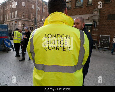 Gardien de sécurité dans la couche fluorescente jaune avec 'London Bridge' Trimestre logo au Shard à Londres, Royaume-Uni KATHY DEWITT Banque D'Images