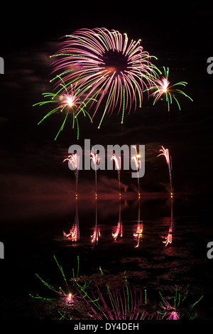 D'Artifice rose et vert reflète dans un lac Sombre Banque D'Images