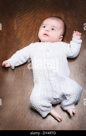 1 - 2 mois bébé garçon couché sur un plancher en bois Banque D'Images